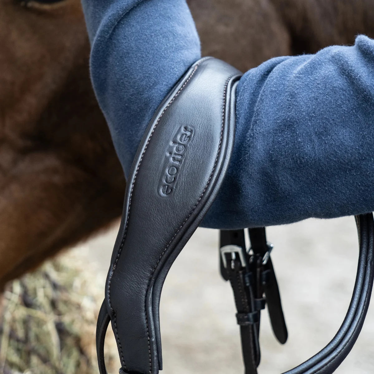 Close-up of an EcoRider anatomical leather headpiece, highlighting the debossed brand logo and thick comfort padding.