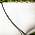 Close-up of a black EcoRider Flexi Rein resting on a grey horse's neck, showcasing the low-profile pimple rubber grip and braided mane.